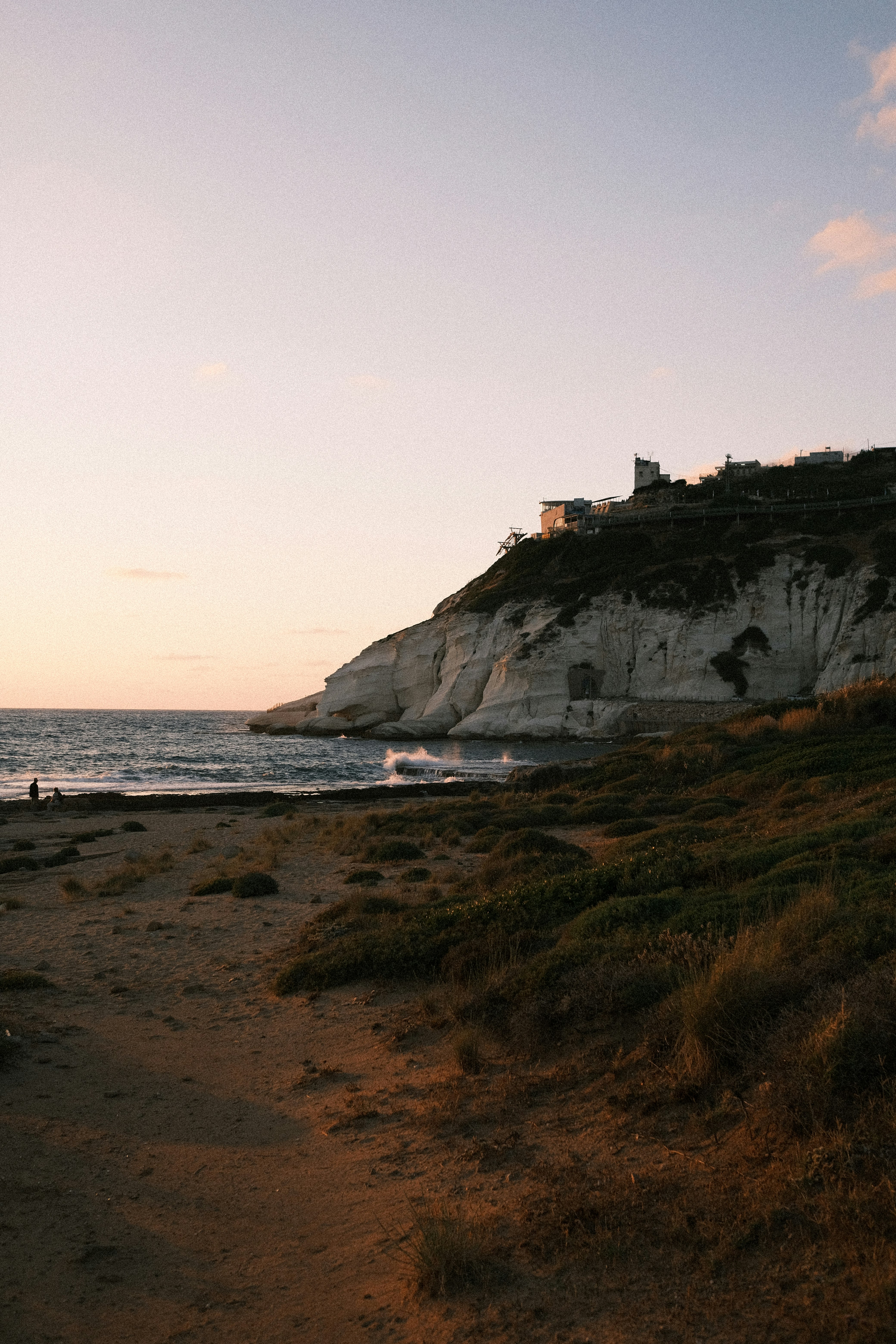 white concrete building on brown rock formation near sea during daytime